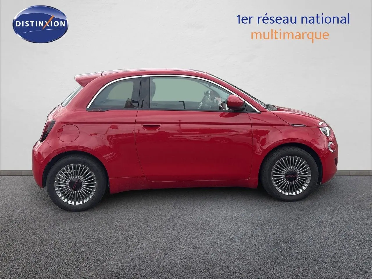 Profil droit d'une FIAT 500e rouge 2024 avec jantes classiques et lignes compactes caractéristiques.