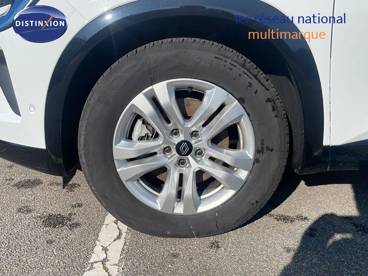 Gros plan sur la roue avant droite du Renault Austral blanc glacier, avec jante argentée et logo Renault central.