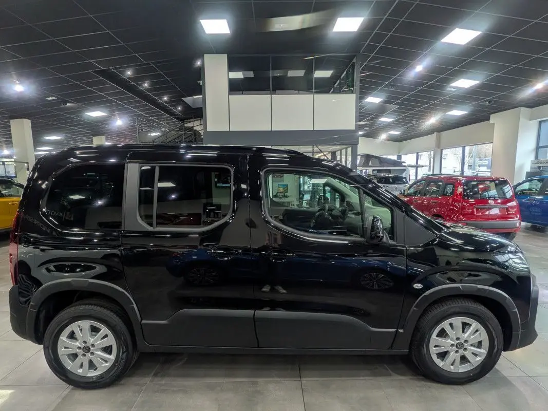 Profil droit d’un Peugeot Rifter Allure noir Perla Nera 2026 en showroom, avec jantes argentées et vitres teintées.