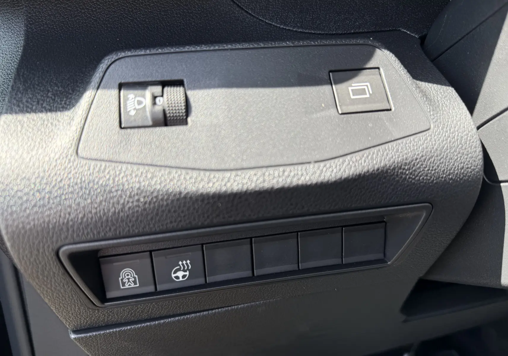 Détail intérieur du tableau de bord noir du Peugeot Rifter 2026, avec commandes de réglage des phares et du volant chauffant.