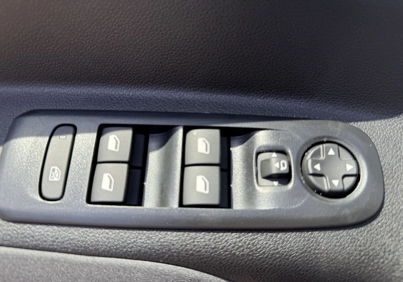 Gros plan sur les commandes de lève-vitres et réglage des rétroviseurs côté conducteur du Peugeot Rifter noir Perla Nera.