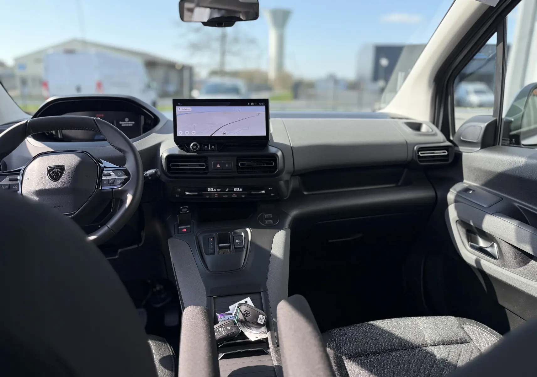 Écran multimédia du Peugeot Rifter Allure 2026 montrant la caméra de recul avec vue arrière sur un intérieur de showroom.