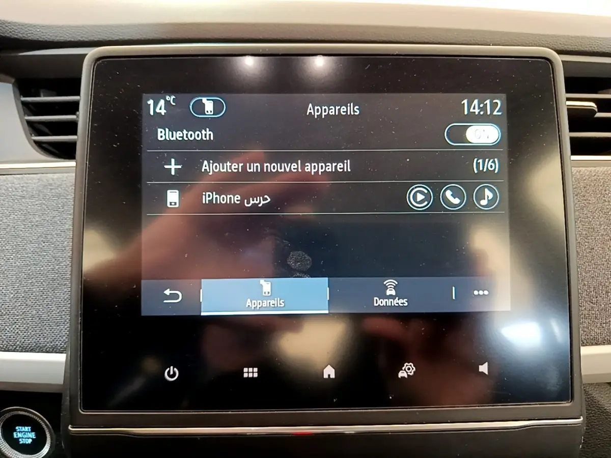 Écran tactile central de la Renault ZOE gris clair, affichant la connexion Bluetooth avec un iPhone.