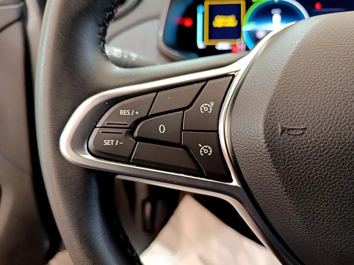 Gros plan sur les commandes de régulateur de vitesse au volant de la Renault ZOE gris clair 2022.