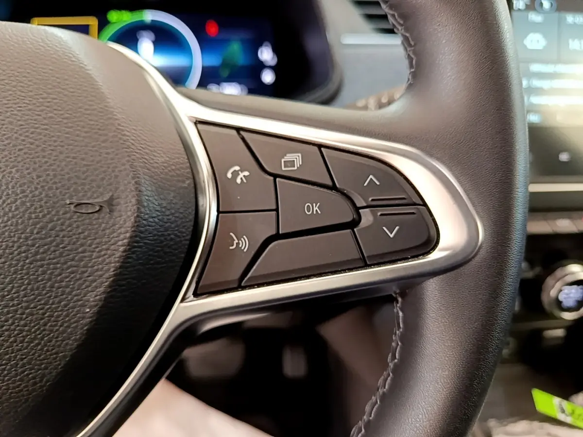 Gros plan sur les commandes au volant à droite de la Renault ZOE gris clair, avec affichage numérique en arrière-plan.
