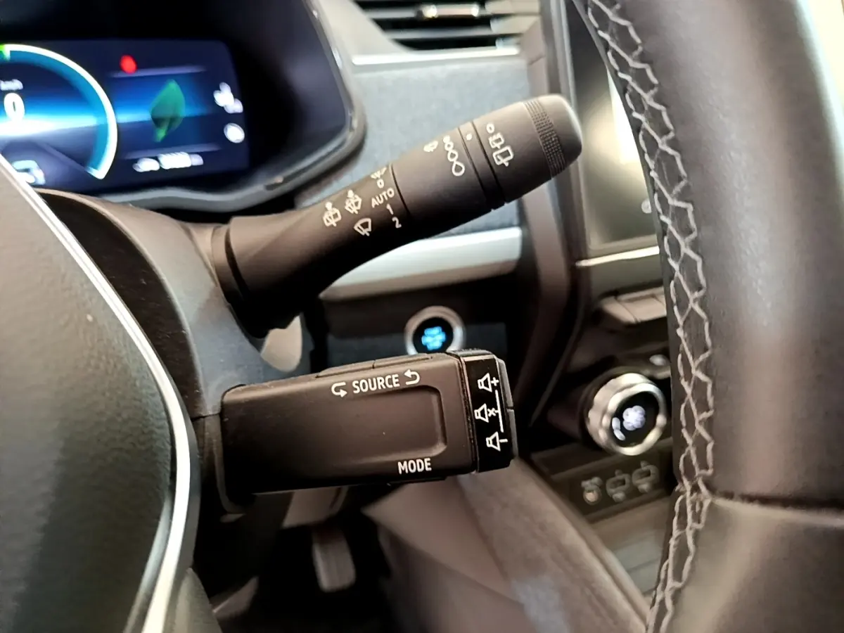 Vue rapprochée du volant et des commandes de la Renault ZOE gris clair, avec tableau de bord digital en arrière-plan.