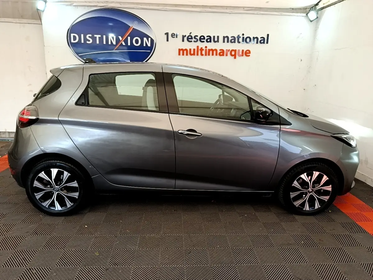 Profil droit d'une Renault ZOE gris clair 2022, version evolution R110, avec jantes alliage et vitres teintées.