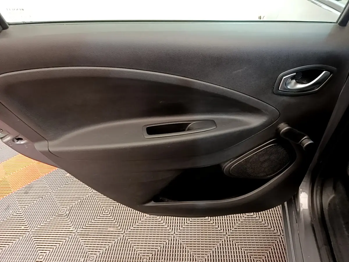 Vue intérieure du panneau de porte avant droit de la Renault ZOE gris clair, avec poignée et haut-parleur intégrés.