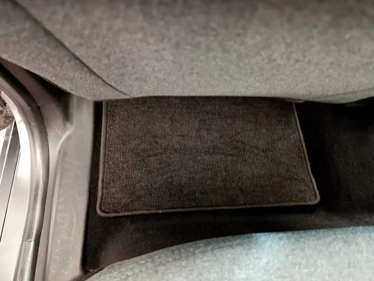 Détail du tapis de sol gris foncé sous le siège conducteur d'une Renault ZOE gris clair 2022 électrique.