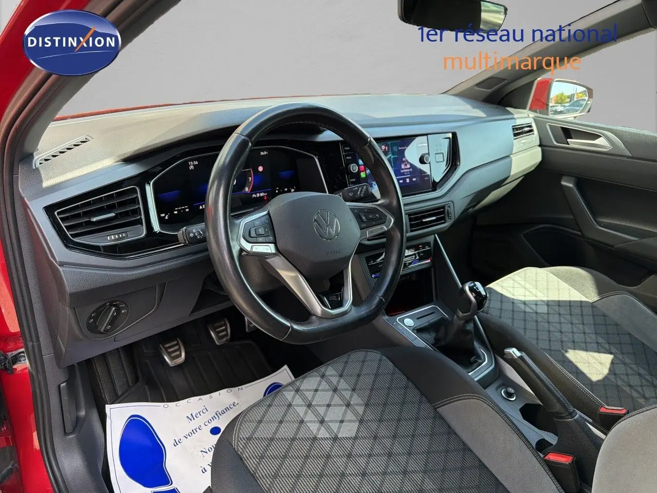 Vue intérieure côté conducteur de la Volkswagen Polo rouge Roi 2023, volant multifonction et tableau de bord numérique.