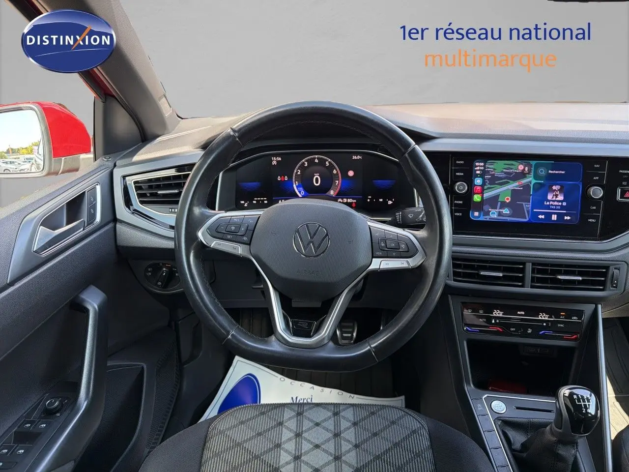 Vue intérieure centrée sur le volant et tableau de bord d’une Volkswagen Polo rouge Roi 2023, boîte manuelle visible.