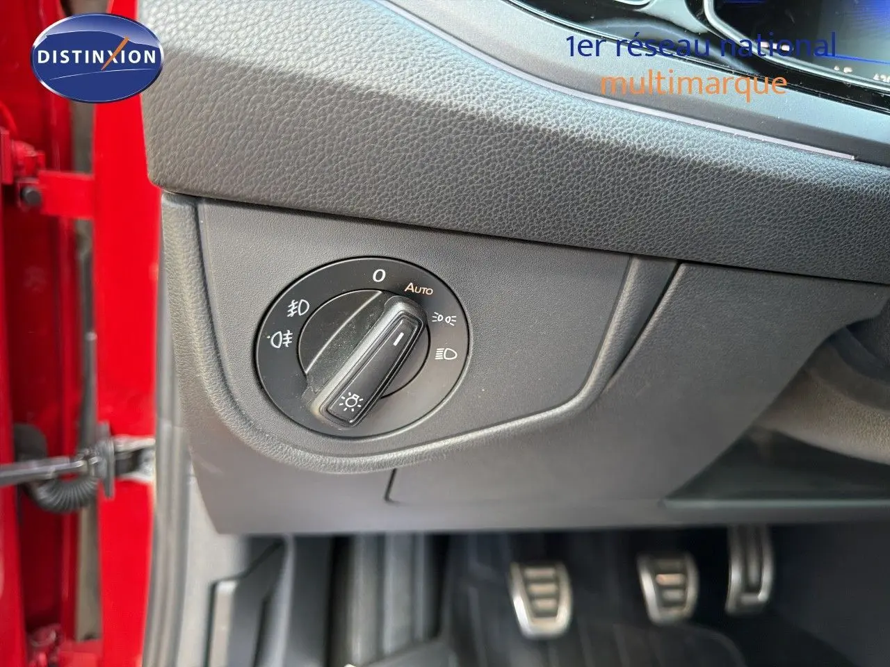 Détail du bouton de commande des phares sur le tableau de bord côté gauche d’une Volkswagen Polo rouge Roi 2023.