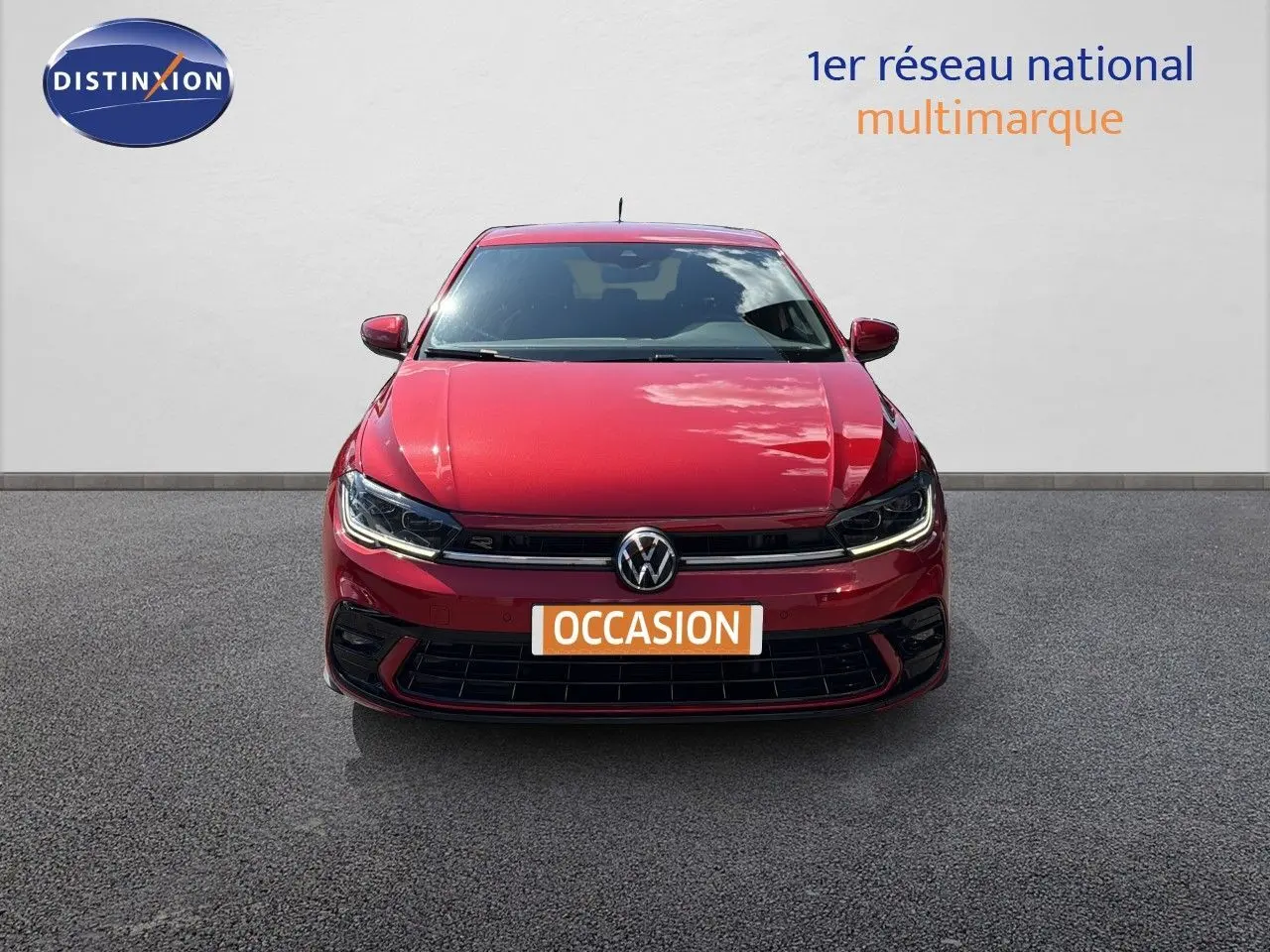 Vue frontale d'une Volkswagen Polo 1.0 TSI 95 R-Line rouge roi avec phares LED allumés sur fond neutre.