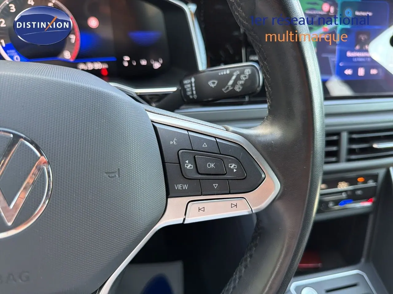 Gros plan sur le volant multifonction noir de la Volkswagen Polo 2023 avec commandes intégrées, tableau de bord en arrière-plan flou.