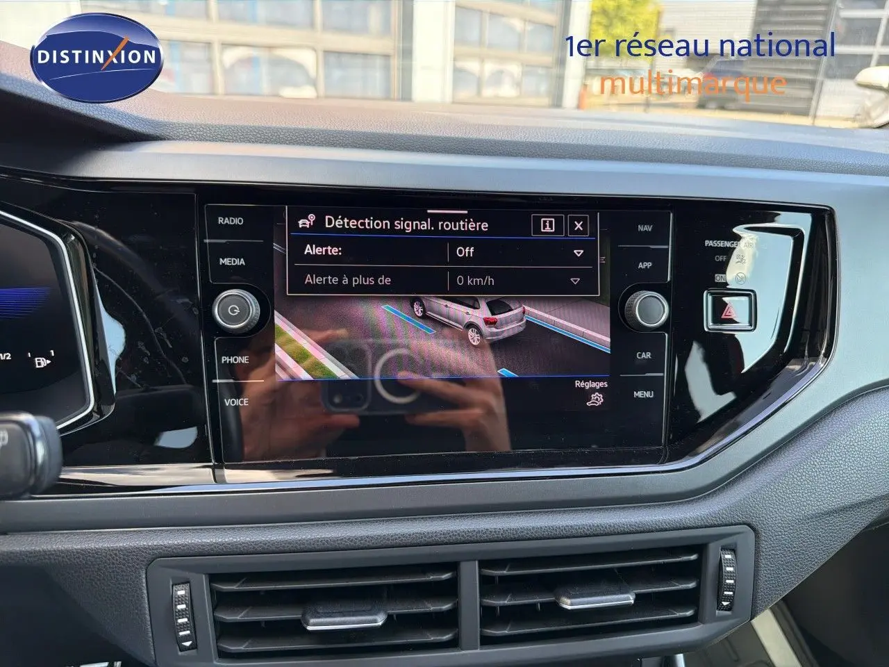 Vue rapprochée de l’écran tactile central du tableau de bord d’une Volkswagen Polo rouge Roi 2023 affichant la détection de signal routier.