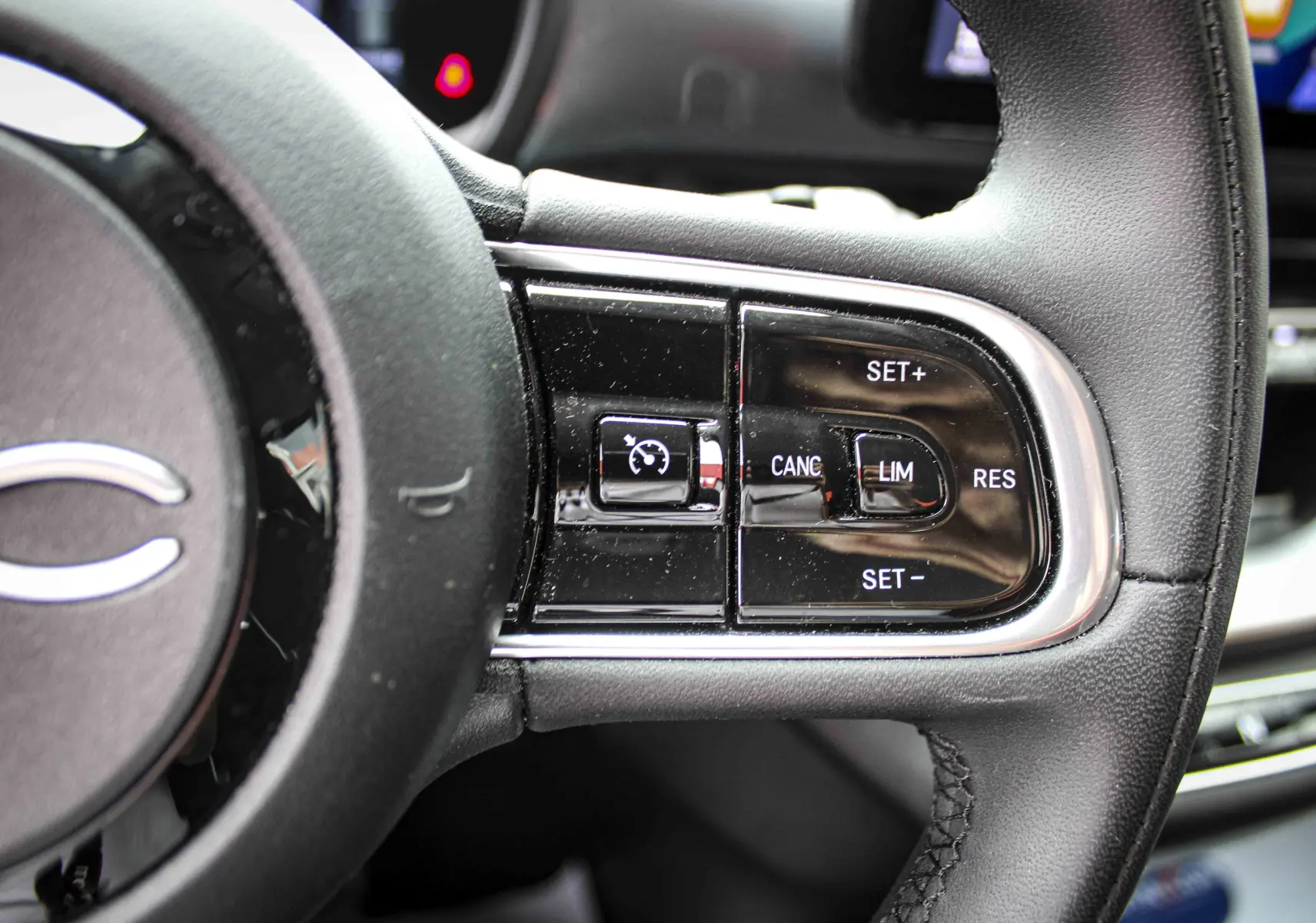 Gros plan sur les commandes de régulateur de vitesse au volant cuir noir de la Fiat 500 électrique gris minéral 2023.