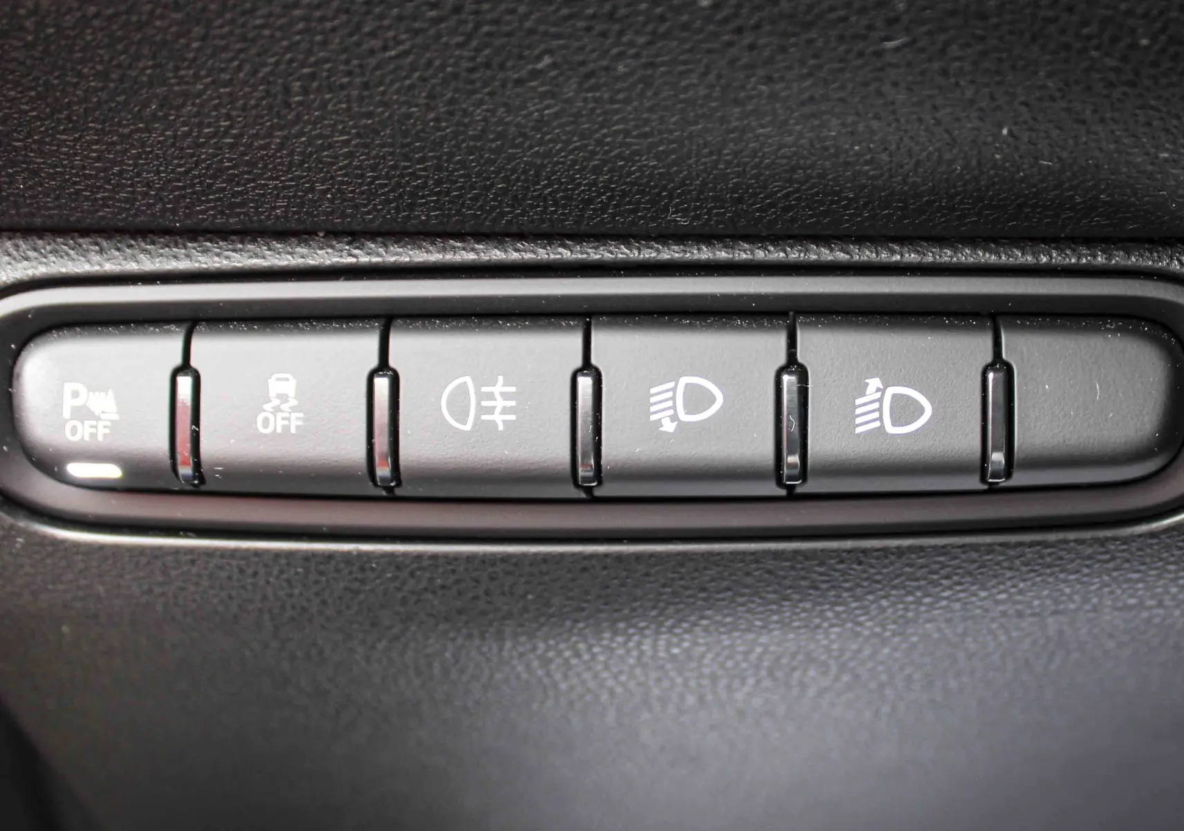 Gros plan sur les boutons de commande d’éclairage et d’assistance de la FIAT 500 électrique 2023, intérieur noir.