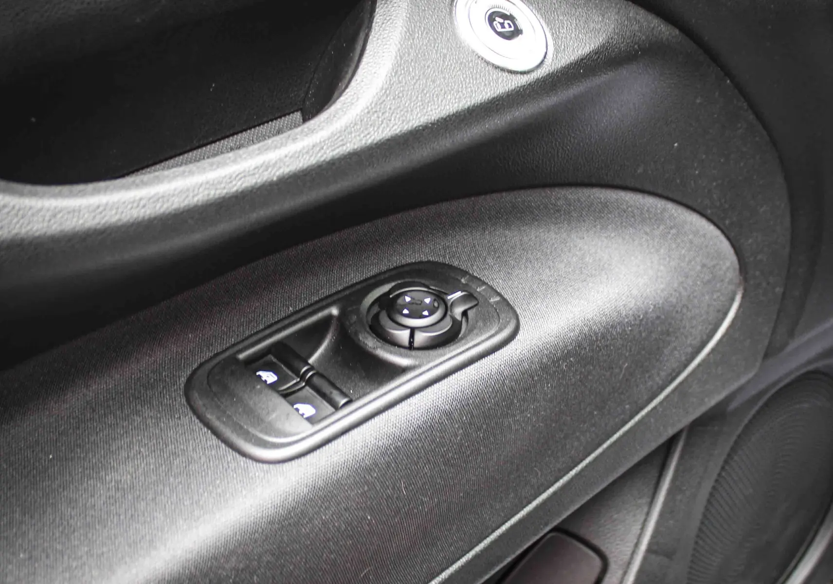 Gros plan sur la commande de réglage des rétroviseurs et des vitres côté conducteur de la FIAT 500 électrique 2023, intérieur noir.