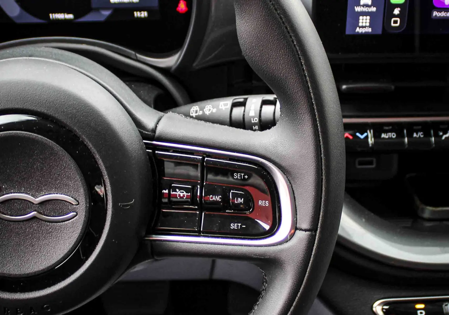 Vue rapprochée du volant et tableau de bord numérique de la Fiat 500 électrique 2023, intérieur noir avec écran tactile CarPlay.