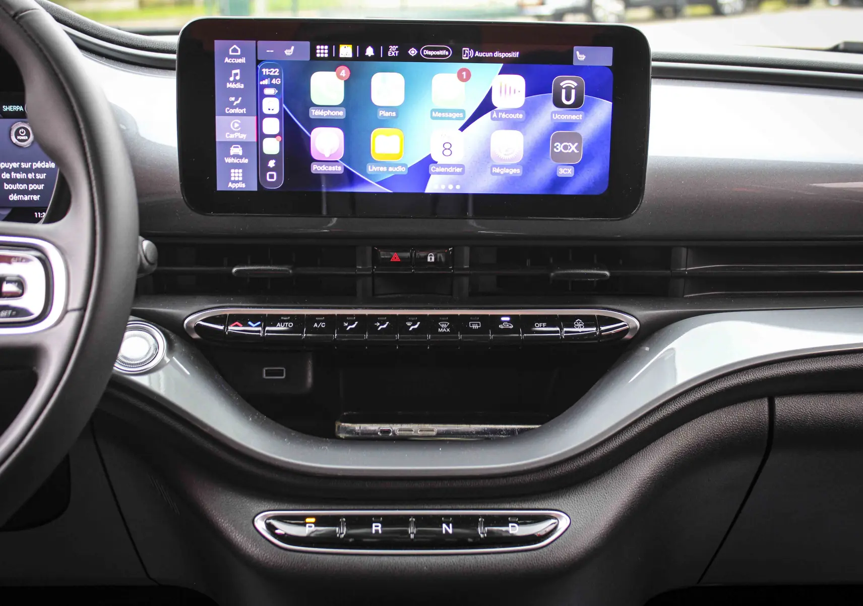 Vue intérieure du tableau de bord de la Fiat 500 électrique gris minéral, avec écran tactile central et commandes de climatisation.