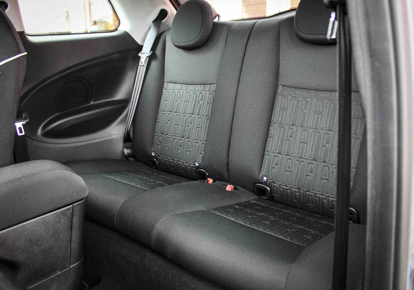 Vue intérieure arrière des sièges noirs avec motif FIAT embossé de la Fiat 500 électrique gris minéral 2023.