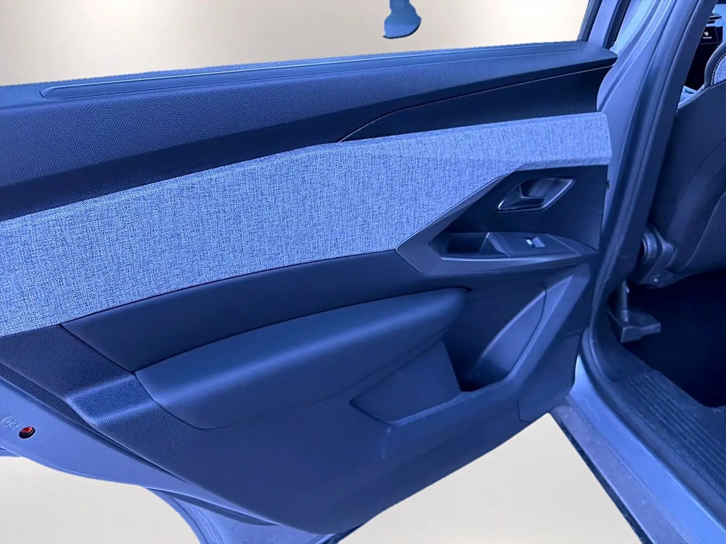 Vue rapprochée de la porte arrière gauche du Peugeot 5008 gris artense, avec insert tissu clair et commandes de vitre.