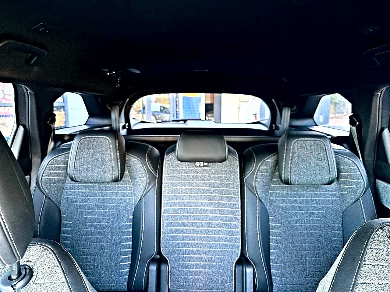 Vue intérieure arrière des sièges gris artense du Peugeot 5008 Hybrid 145 allure e-dcs6 avec appuis-tête et ceintures visibles.