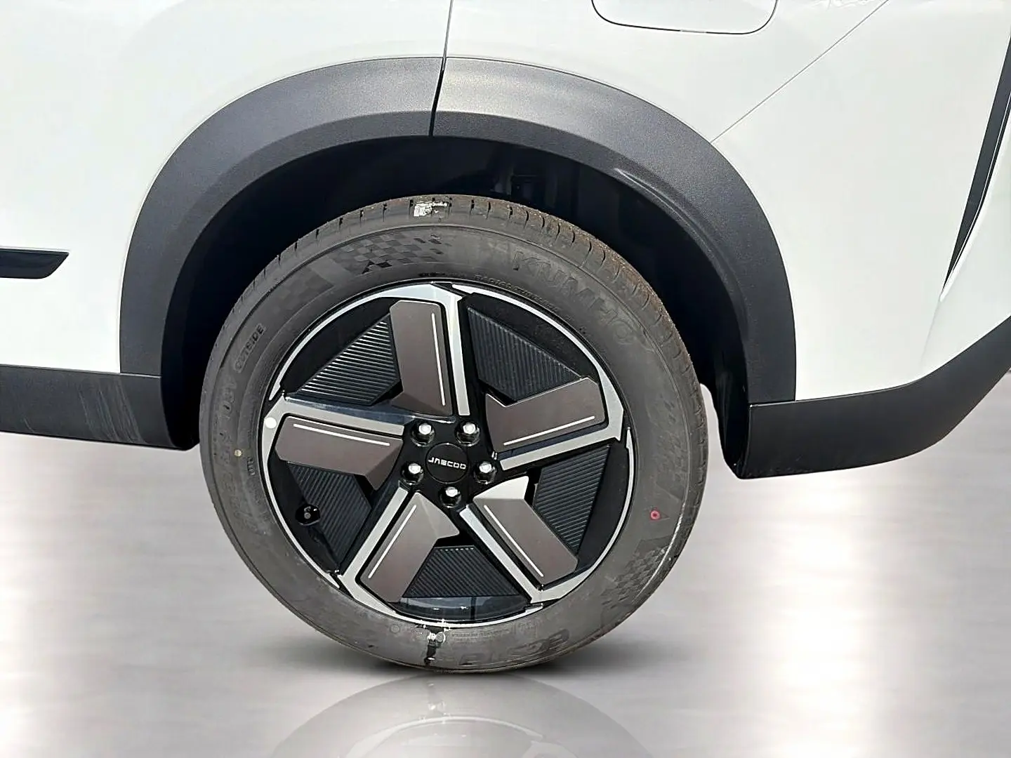 Gros plan sur la roue avant gauche du JAECOO J7 blanc kaki avec jante alu noire et grise au design moderne.