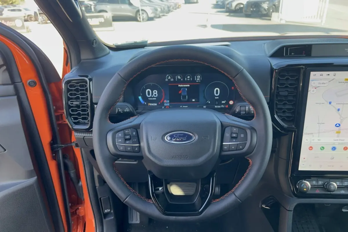Vue intérieure centrée sur le volant cuir noir avec surpiqûres orange du Ford Ranger Wildtrak 2026 Ignite Orange.