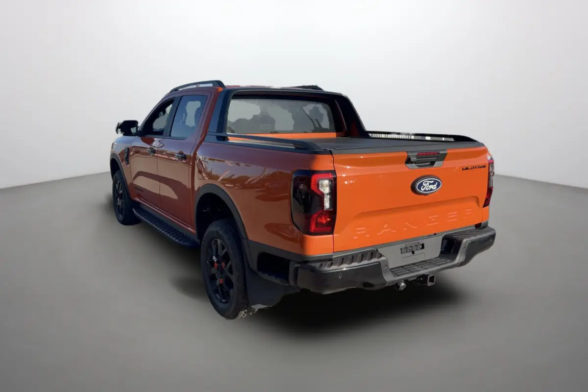 Ford Ranger Wildtrak orange Ignite en 3/4 arrière droit, avec benne couverte et jantes noires.
