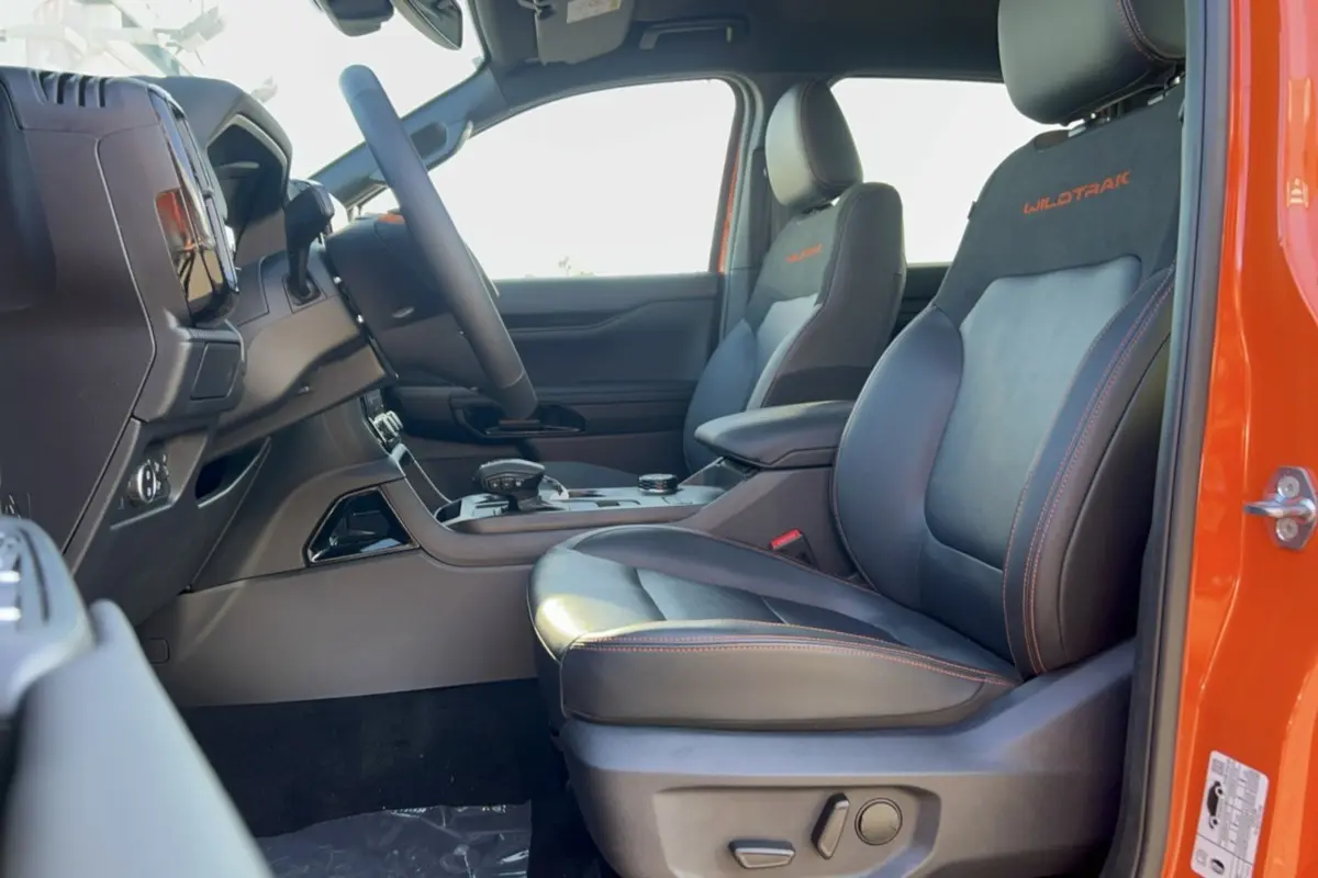 Vue intérieure côté droit du Ford Ranger Wildtrak orange, sièges cuir noirs avec surpiqûres orange et logo brodé.