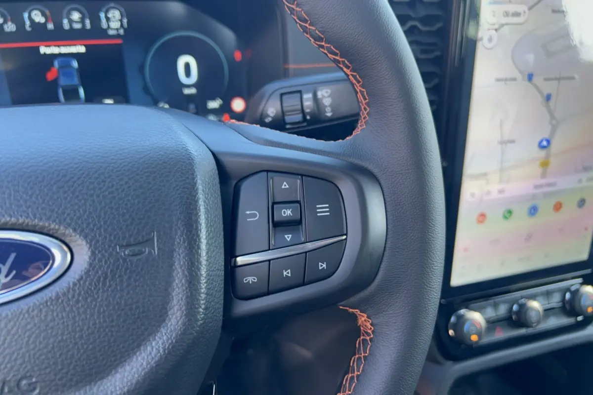 Gros plan sur le volant cuir noir avec surpiqûres orange et commandes multifonctions du Ford Ranger Wildtrak 2026.
