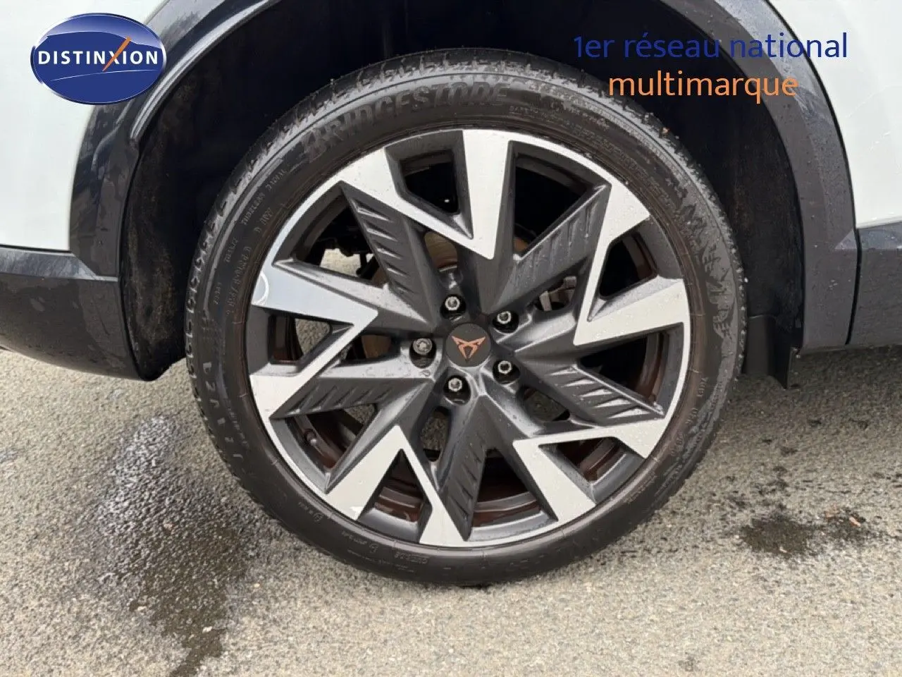 Gros plan sur la roue avant droite du CUPRA Formentor blanc neige métal, mettant en valeur la jante bi-ton au design anguleux.