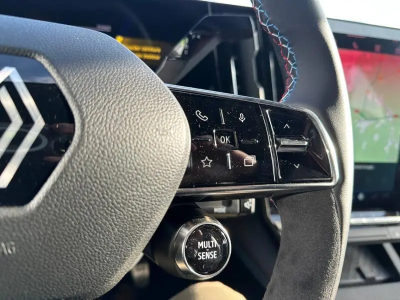 Gros plan sur le volant multifonction du Renault Scenic E-Tech gris, avec commandes tactiles et bouton Multi-Sense visible.