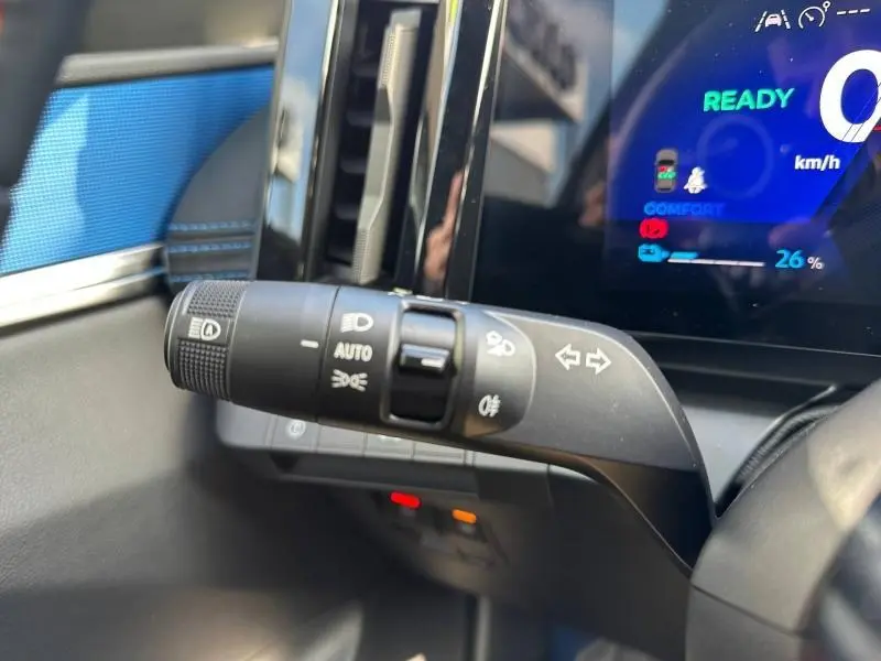 Gros plan sur la commande des feux et clignotants dans l’habitacle gris et bleu du Renault Scenic E-Tech 2025.