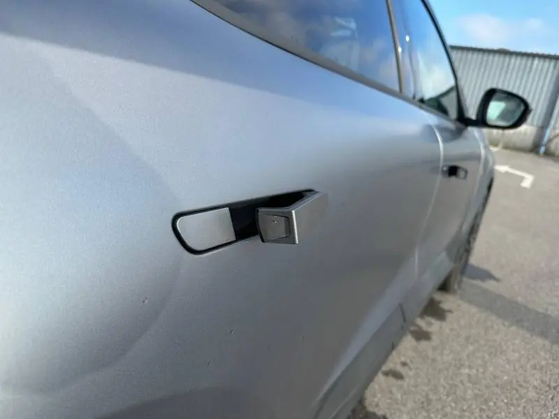 Gros plan sur la poignée de porte déployée côté droit d’un Renault Scenic E-Tech gris schiste, vue en légère plongée.