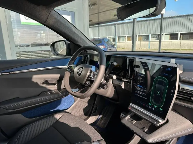 Vue intérieure côté conducteur du Renault Scénic E-Tech gris Schiste, avec grand écran tactile vertical et volant multifonction.