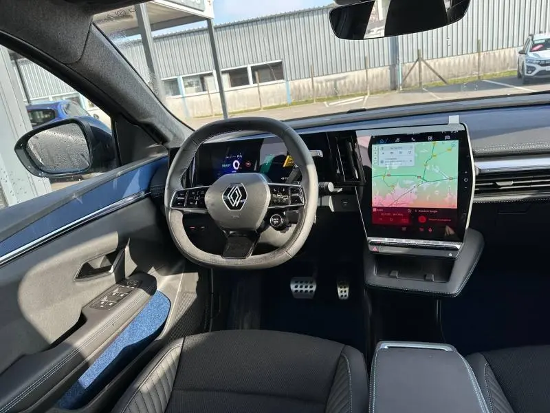 Vue intérieure avant du Renault Scénic E-Tech gris Schiste, volant multifonction et grand écran tactile central avec GPS.