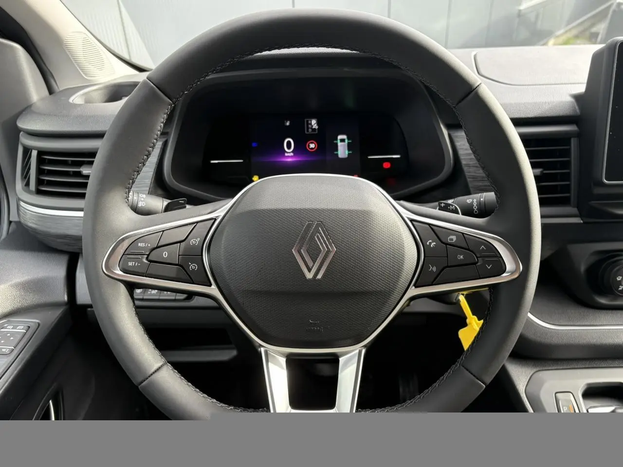 Vue rapprochée du volant multifonction noir avec logo Renault et tableau de bord numérique du Trafic Fourgon blanc.