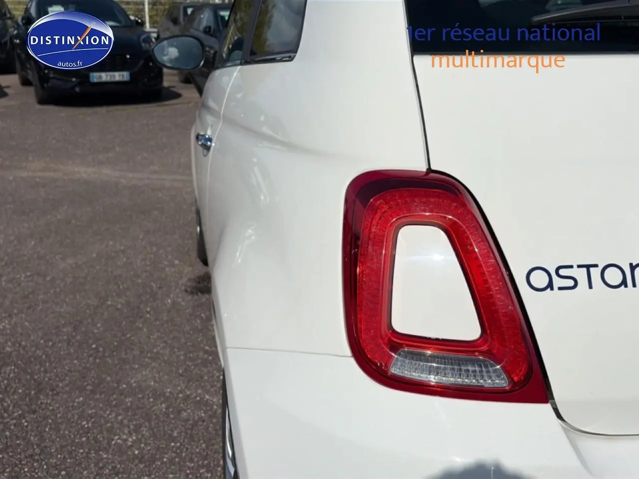 Gros plan sur le feu arrière droit d'une FIAT 500 blanche, vue arrière côté droit, avec reflet sur la carrosserie.