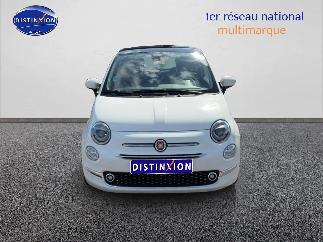 Vue avant d'une Fiat 500 blanche 2023 avec toit panoramique et phares ronds caractéristiques.