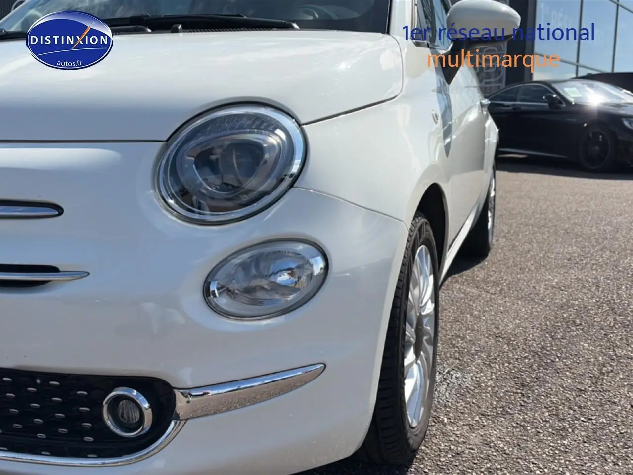 Vue 3/4 avant droit d'une Fiat 500 blanche mettant en valeur ses phares ronds et jantes alu brillantes.