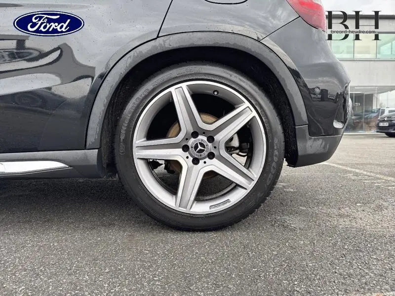 Gros plan sur la roue arrière droite d'une Mercedes GLA 180 d Fascination noire avec jante AMG multibranches 19 pouces.