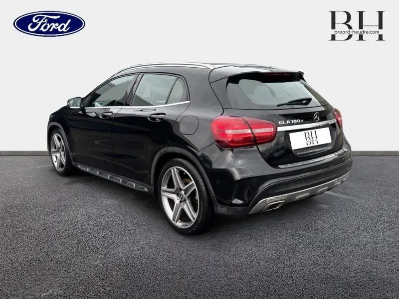 Mercedes GLA 180 d noir cosmos en vue 3/4 arrière droit, avec jantes AMG 19 pouces multibranches et échappement chromé double sortie.