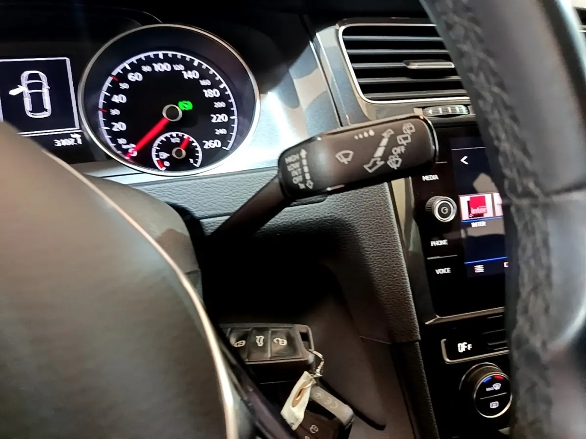 Vue intérieure du tableau de bord de la Volkswagen Golf noir, avec volant cuir et compteur digital lumineux.