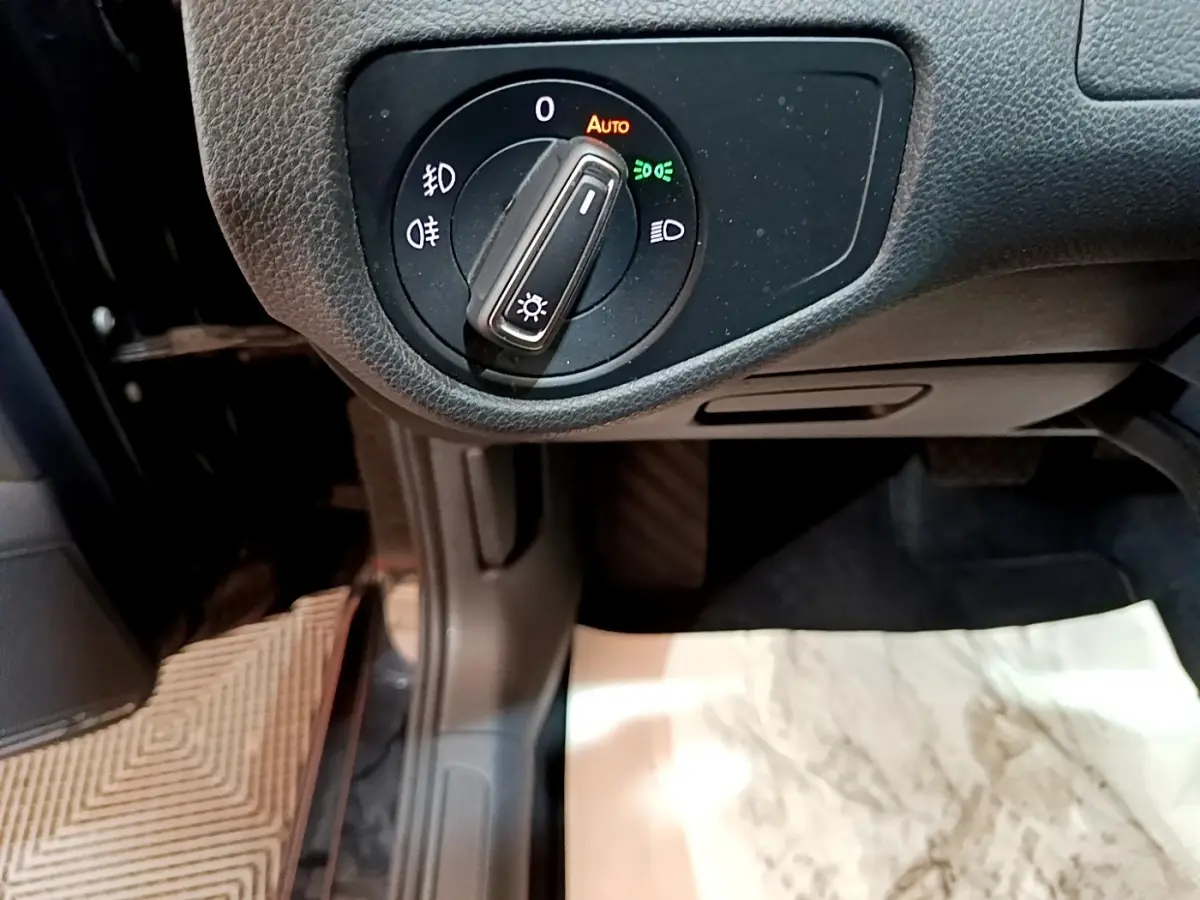 Gros plan sur la molette de réglage des phares dans l'habitacle d'une Volkswagen Golf noire 2019.