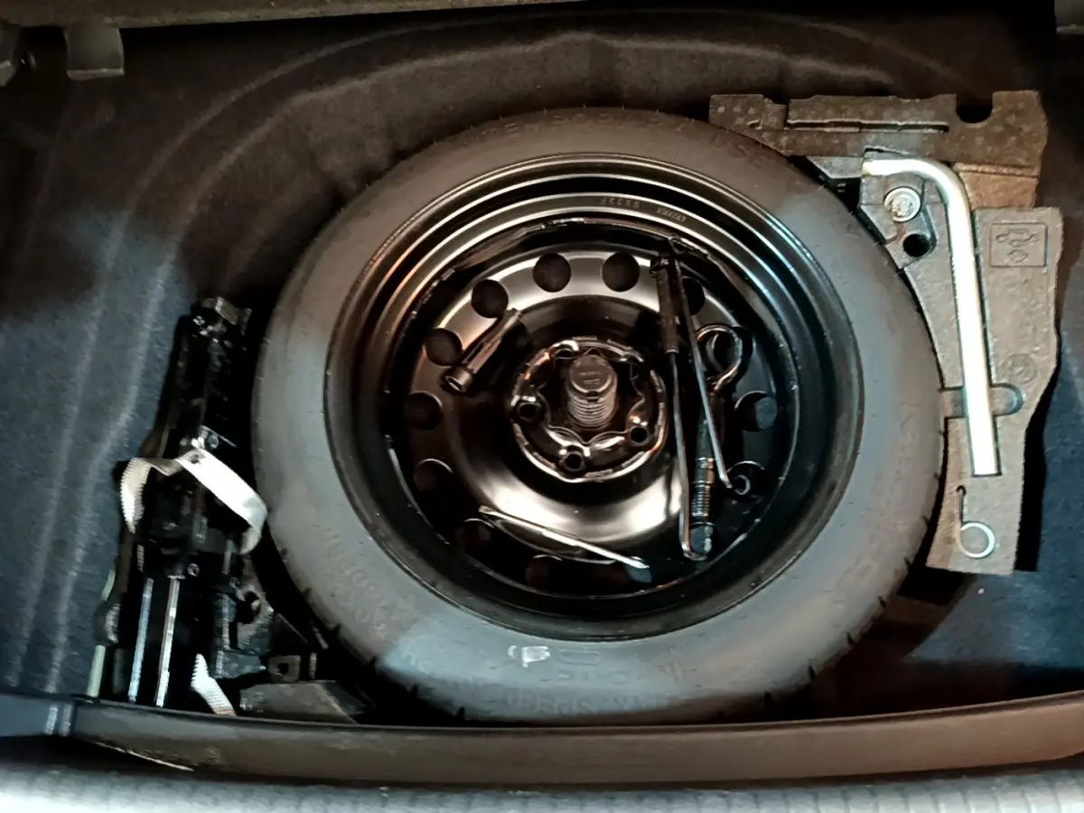 Vue plongeante sur la roue de secours et outils de bord dans le coffre d'une Volkswagen Golf noire 2019.