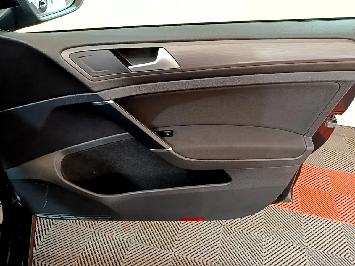 Vue intérieure de la porte avant gauche noire de la Volkswagen Golf 2019 avec insert bois et poignée argentée.