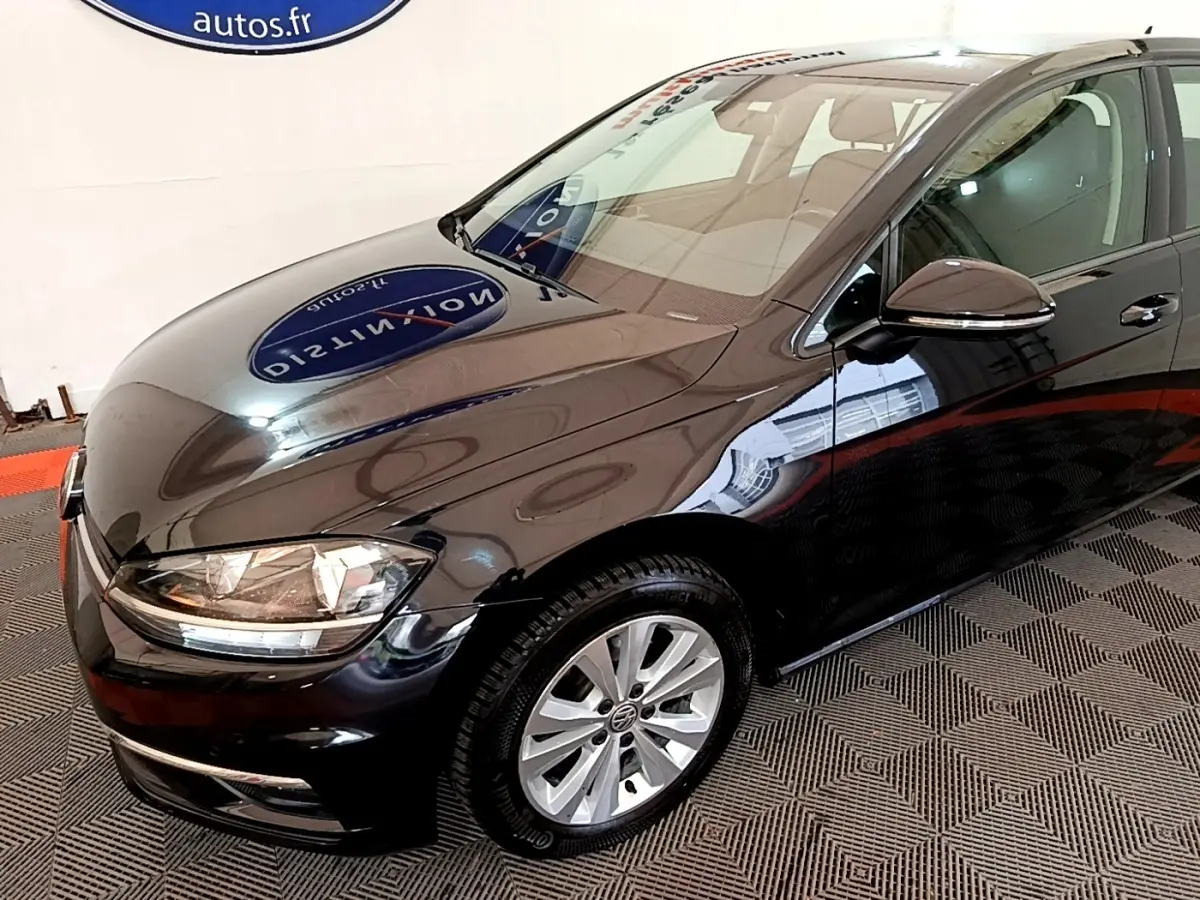 Vue 3/4 avant droite d'une Volkswagen Golf noire brillante avec jantes alliage et rétroviseur électrique.