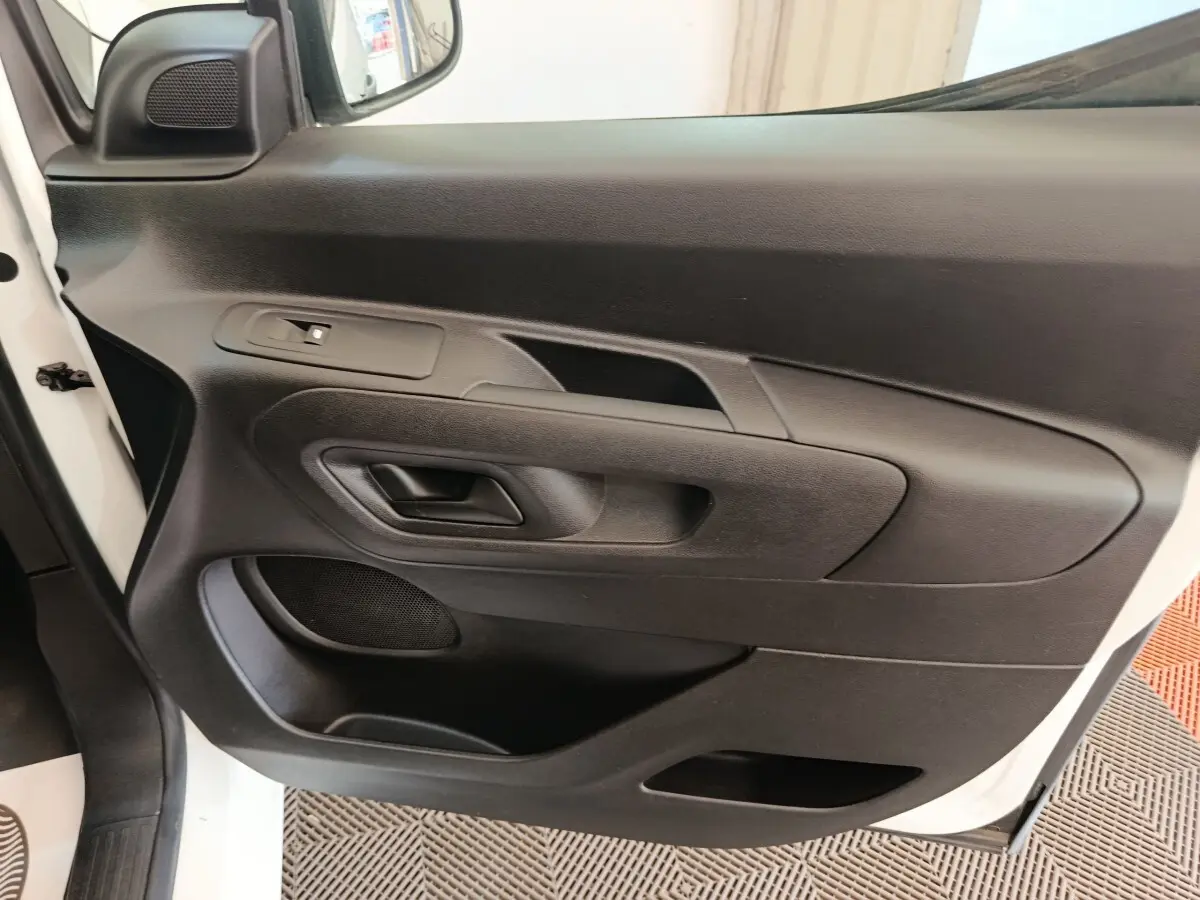 Vue rapprochée de la porte avant gauche noire du Citroën Berlingo blanc 2021 avec poignée et haut-parleur intégrés.